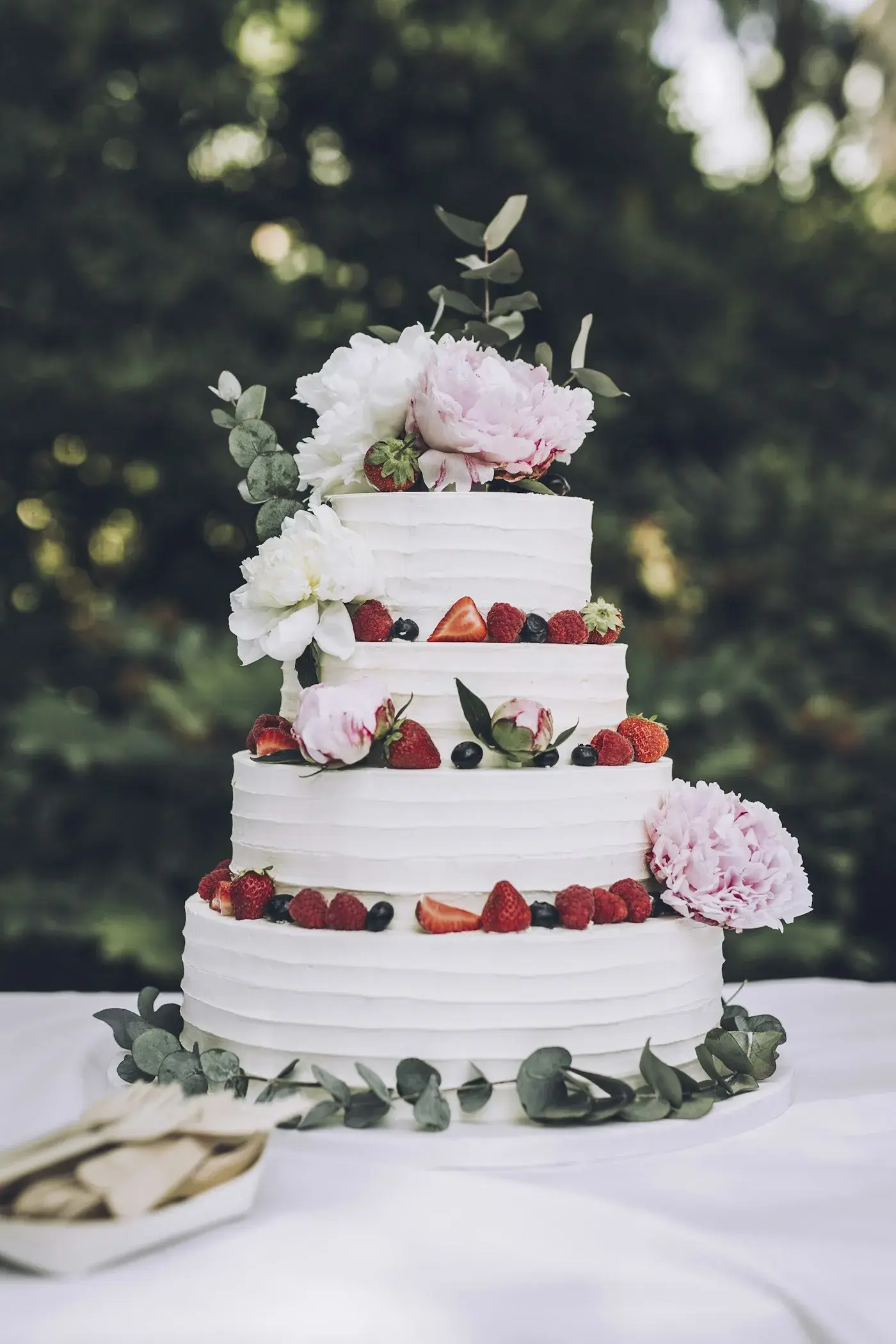Tiered naked-style wedding cake with peonies and berries